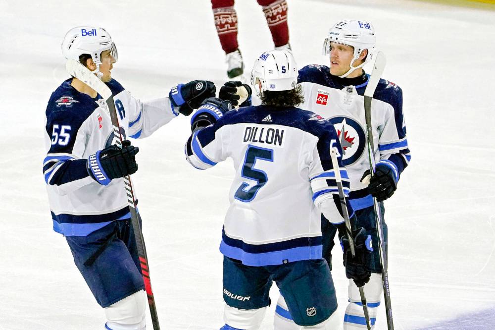 Winnipeg Jets’ Mark Scheifele (55) gets fist-bumps from Brenden Dillon (5) and Nikolaj Ehlers (27) after scoring against the Arizona Coyotes during the third period. (Darryl Webb / The Associated Press)