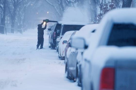 Jamie Muzik clears off his vehicle with a leaf blower on Ruby Street Thursday morning. (Mike Deal / Winnipeg Free Press)