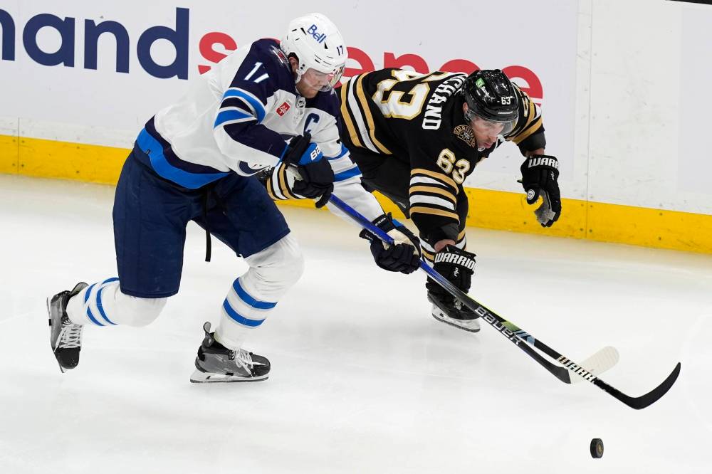 (AP Photo/Michael Dwyer)
Winnipeg Jets’ Adam Lowry and Boston Bruins’ Brad Marchand battle for the puck during the second period Monday, in Boston.