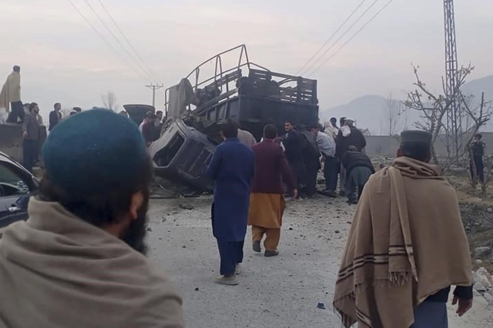 In this photo released by Rescue 1122 Emergency Department, rescue workers and local residents examine a damage vehicle at the site of bomb explosion, in Mamund, Pakistan, Monday, Jan. 8, 2024. A roadside bomb exploded Monday near a van carrying police assigned to protect workers in an anti-polio immunization campaign in restive northwestern Pakistan, killing and wounding officers and others, officials said. (Rescue 1122 Emergency Department vis AP)
