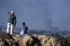 People watch smoke rising to the sky after an explosion in the Gaza Strip, as seen from southern Israel, Saturday, Jan. 6, 2024. An Ontario woman fears the death of her brother during the conflict in Gaza means her pregnant sister-in-law will not qualify for a federal program to help extended family members of Canadians escape to safety. THE CANADIAN PRESS/AP/Leo Correa