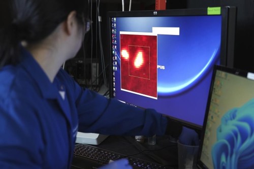 Naixin Qian, a Columbia physical chemist, zooms in on an image generated from a microscope scan, with nanoplastics, microscopic plastic pieces, appearing as bright red dots in New York on Monday, Jan. 8, 2024. A new study found the average liter of bottled water has nearly a quarter million invisible pieces of nanoplastics, detected and categorized for the first time by a microscope. (AP Photo/Mary Conlon)