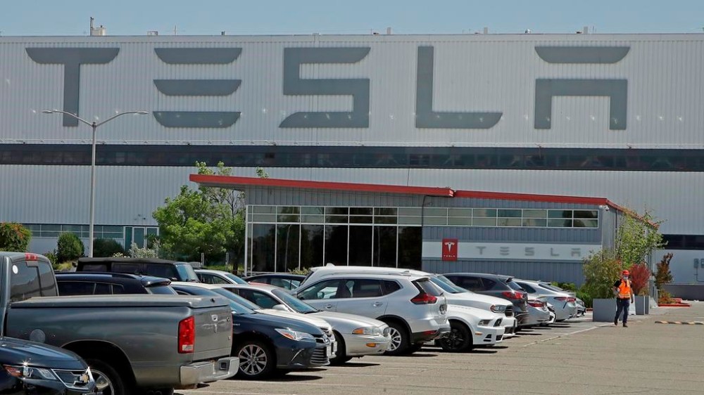 FILE - A man walks in the Tesla plant parking lot, May 11, 2020, in Fremont, Calif. Factory workers at Tesla have been told to expect pay raises in 2024, a move that comes as the United Auto Workers union tries to organize the electric vehicle maker's U.S. plants. The UAW said Thursday, Jan. 11, 2024, that Tesla workers have told the union about company statements on the raises, which did not give details about the size of the increases. (AP Photo/Ben Margot, File)
