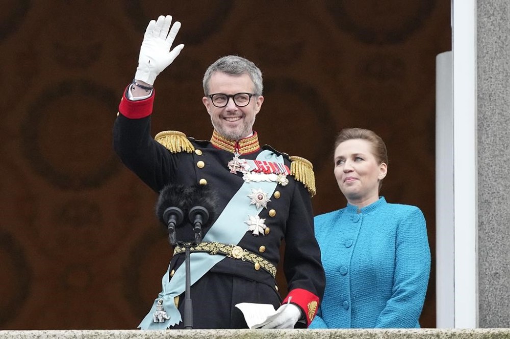 Denmark's King Frederik X waves from the balcony of Christiansborg Palace as Danish Prime Minister Mette Frederiksen looks on in Copenhagen, Denmark, Sunday, Jan. 14, 2024. Queen Margrethe II has become Denmark's first monarch to abdicate in nearly 900 years when she handed over the throne to her son, who has become King Frederik X. (AP Photo/Martin Meissner)