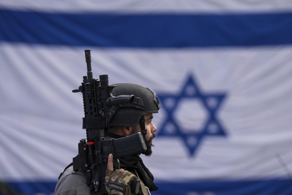 An Israeli border police officer stands guard at the site of a Palestinian car-ramming and stabbing attack at a bus stop in Ra'anana, Israel, Monday, Jan. 15, 2024. Israeli police say a car-ramming and stabbing attack by Palestinians killed a woman and wounded at least 12 others north of Tel Aviv. (AP Photo/Oded Balilty)