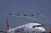 Akasa Air's 737-8 aircraft is seen in foreground as Indian Air Force Sarang helicopters perform an aerobatic display during the 'Wings India 2024,' a biennial aviation event at Begumpet airport in Hyderabad, India, Thursday, Jan. 18, 2024. (AP Photo/Mahesh Kumar A.)