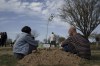Friends and relatives sit next to a tree they planted in memory of a person who was killed on Oct. 7 in a cross-border attack by Hamas at the Nova music festival in Re'im, Southern Israel, Sunday, Jan. 21, 2024, during a tree planting event. (AP Photo/Leo Correa)