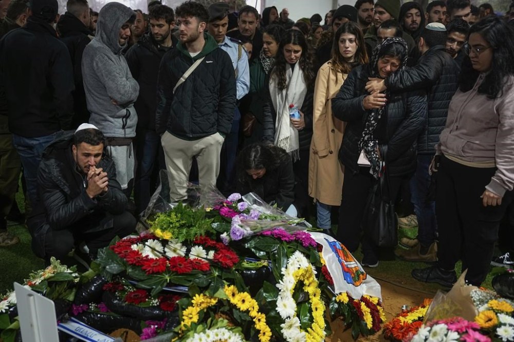 Family and friends of Israeli reservist Hadar Kapeluk mourn over his grave during his funeral at Mt. Herzl military cemetery in Jerusalem, Tuesday, Jan. 23, 2024. Kapeluk, 23, was killed during Israel's ground operation in the Gaza Strip, where the Israeli army has been battling Palestinian militants in the war ignited by Hamas' Oct. 7 attack into Israel. (AP Photo/Ohad Zwigenberg)