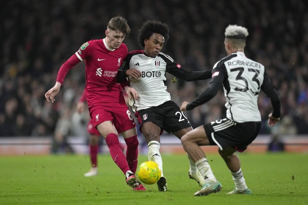 Liverpool's Conor Bradley, left, and Fulham's Willian, center, vie for the ball during the English League Cup semi final second leg soccer match between Fulham and Liverpool, at Craven Cottage stadium in London, England, Wednesday, Jan. 24, 2024. (AP Photo/Kin Cheung)