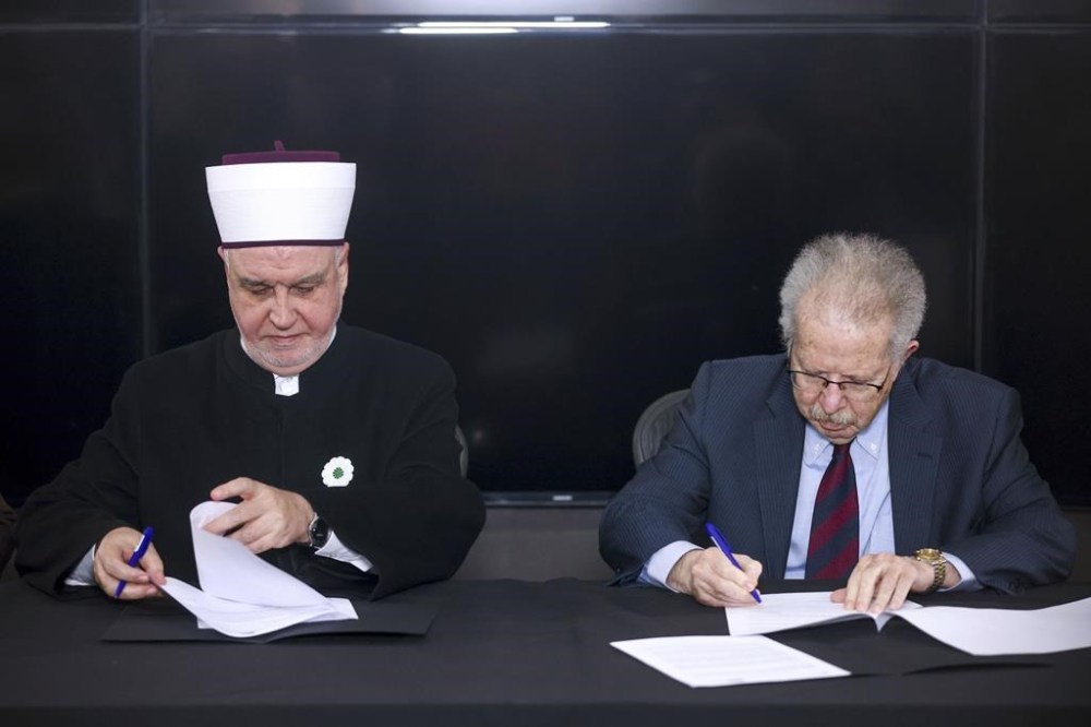 Associate Vice President of the World Jewish Congress Menachem Rosensaft, right, signs a document representing Muslim-Jewish peace initiative, with the Bosnian Grand Mufti Husein Kavazovic, at the Srebrenica Memorial Center, on International Holocaust Remembrance Day, in Potocari, Bosnia, Saturday, Jan. 27, 2024. Jews and Muslims from Bosnia and abroad gathered in Srebrenica Saturday to jointly observe International Holocaust Remembrance Day and promote compassion and dialogue amid rising global sectarian hatred fueled by Israel’s war in Gaza. (AP Photo/Armin Durgut)