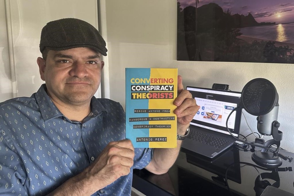 Antonio Perez holds his book