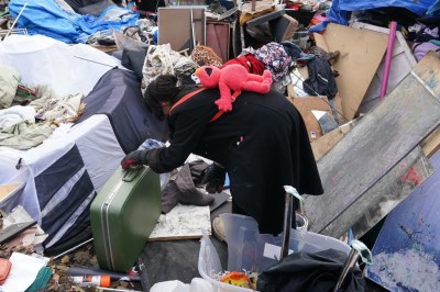 A woman looks through some belongings outside of the St. Stephen-In-The-Fields Anglican Church in Toronto as the city begins clearing out the encampment on Friday Nov. 24, 2023. New research published today says people who are homeless have high rates of COVID-19 reinfection. THE CANADIAN PRESS/Chris Young