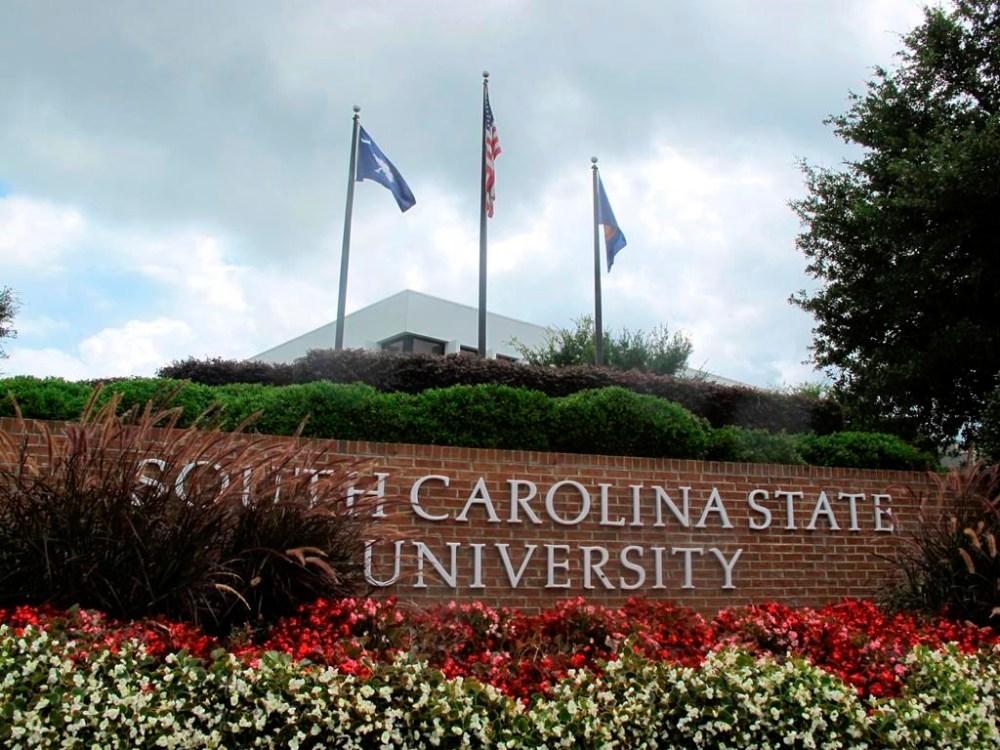 FILE - In this July 22, 2014, file photo, flags fly at the entrance to South Carolina State University in Orangeburg, S.C. A student faces charges after a shooting at South Carolina State University on Tuesday, Feb. 6, 2024 that sent the campus into lockdown for nearly one hour but did not leave any reported injuries. (AP Photo/Bruce Smith, File)