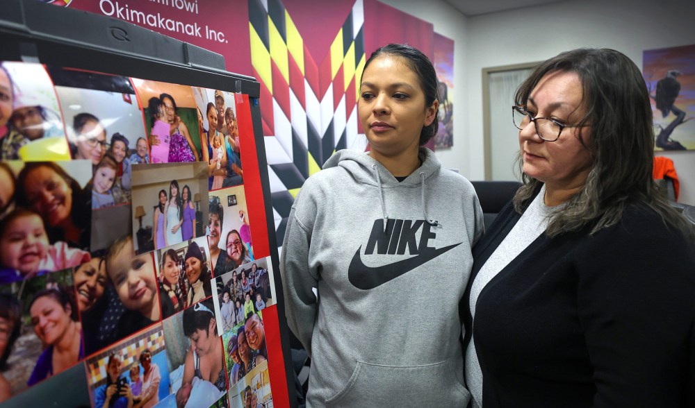 Noreen Tait's daughter, Brandy (left) and sister, Arla Tait-Linklater, pause to look at a collage of photos of Noreen after the Manitoba Keewatinowi Okimakanak Winnipeg office Monday. (Ruth Bonneville / Winnipeg Free Press)