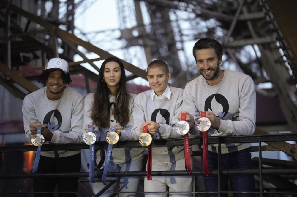 Paris 2024 Olympics Organizing Committee President Tony Estanguet, right, French athletes Marie Patouillet, center right, Sara Balzer, center left, and Arnaud Assoumani, left, present the Paris 2024 Olympic and Paralympic medals at the Eiffel Tower, in Paris, Thursday, Feb. 1, 2024. A hexagonal, polished piece of iron taken from the Eiffel Tower is being embedded in each gold, silver and bronze medal that will be hung around athletes' necks at the July 26-Aug. 11 Paris Games and Paralympics that follow. (AP Photo/Thibault Camus)