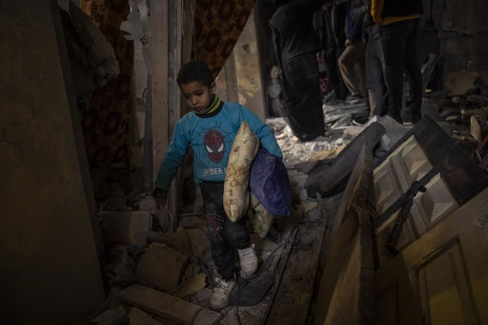 Palestinians collect their belongings from their damaged house after an Israeli airstrike in Rafah, southern Gaza Strip, Thursday, Feb. 8, 2024. (AP Photo/Fatima Shbair)