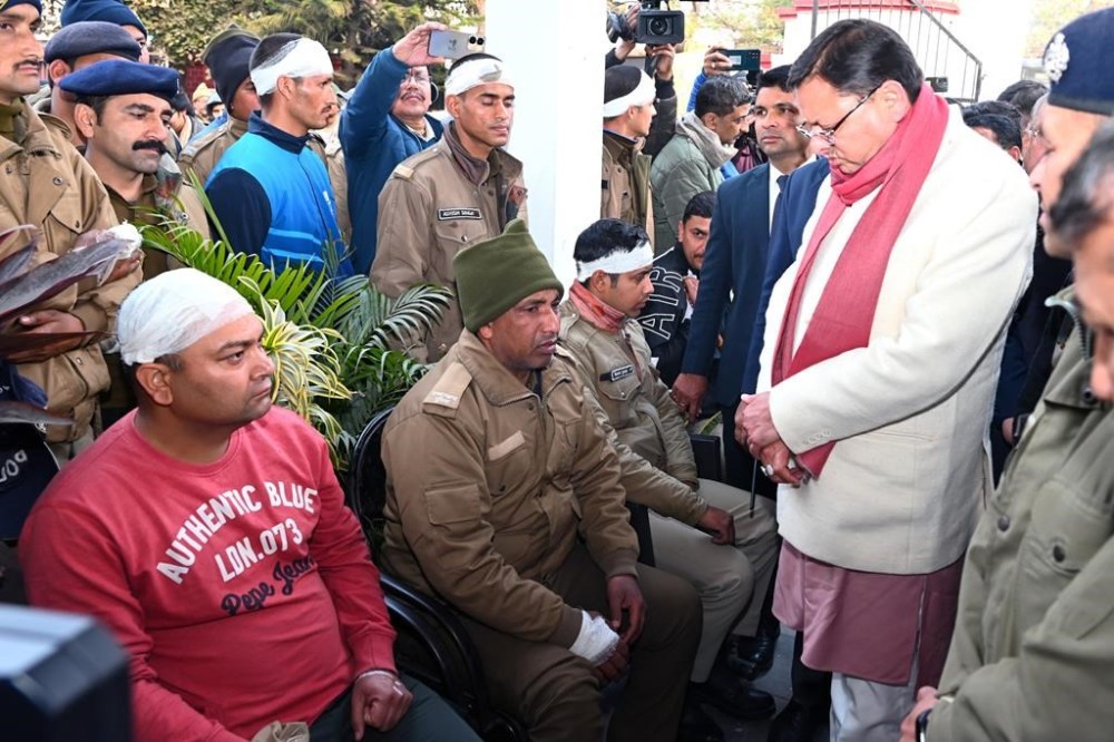 This photograph shared by Uttarakhand Chief Minister Pushkar Singh Dhami on his social media platform X shows him, right, in white jacket, meeting with the policemen injured in clashes over the construction of a Muslim seminary and a mosque in Haldwani in the Uttarakhand state, India, Friday, Feb. 9, 2024. (Pushkar Singh Dhami on X via AP)