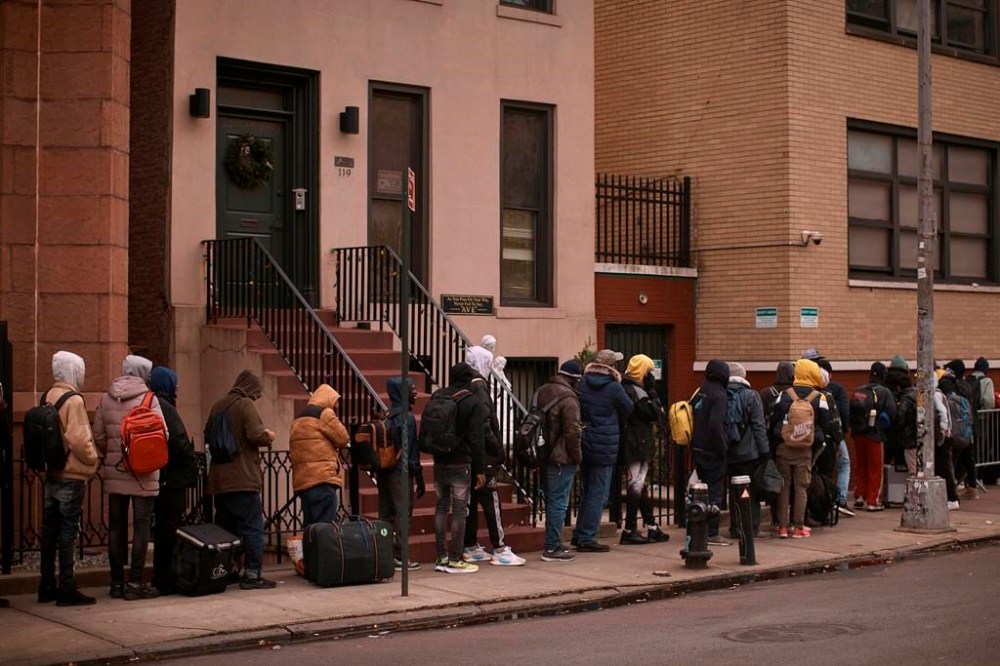 FILE - Migrants queue in the cold as they look for a shelter outside a migrant assistance center at St. Brigid Elementary School on Tuesday, Dec. 5, 2023, in New York. On Friday, Feb. 9, 2024 The Associated Press reported on stories circulating online incorrectly claiming New York City is giving credit cards to migrants living in the U.S. illegally. (AP Photo/Andres Kudacki, File)