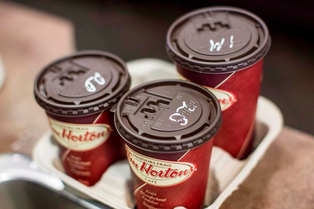 Restaurant Brands International Inc. reported its fourth-quarter net income more than doubled compared with a year ago. Cups of coffee sit on a counter in a Tim Hortons outlet in Oakville, Ont. on Monday September 16, 2013. THE CANADIAN PRESS/Chris Young