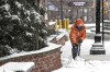 An employee of One Wall Street Apartments in Attleboro, Mass. shovels snow from the sidewalk next to the complex Tuesday, Feb. 13, 2024 as heavy snow falls on Tuesday, Feb. 13, 2024. Several inches of snow is forecasted for the southeastern section of Massachusetts. (Mark Stockwell /The Sun Chronicle via AP)
