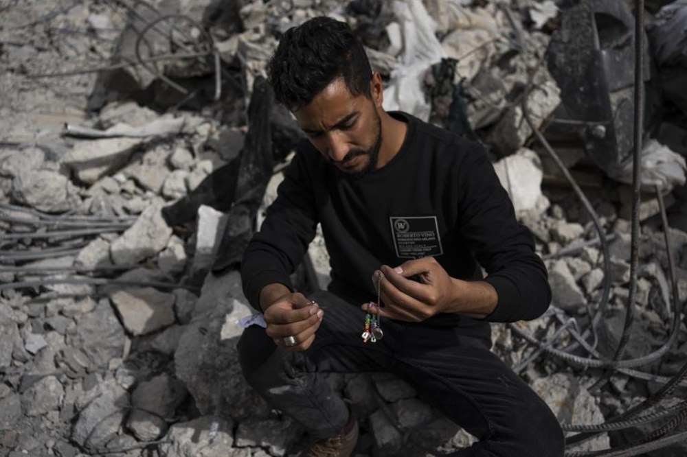Ibrahim Hasouna, center, the sole survivor among his family, sits amidst the debris of his bombed home in Rafah, southern Gaza Strip, Tuesday, Feb. 13, 2024. On Monday, February 12, Hasouna lost eight family members, including three children, He says the house was bombed during an Israeli operation to rescue hostages held in a building in another part of town. (AP Photo/Fatima Shbair)