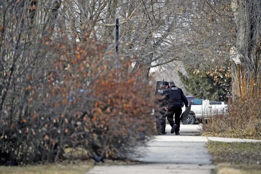 Two Gillette Police officers carry shields near a residence where a suspect barricaded himself during a standoff, Tuesday, Feb. 13, 2024, in Sheridan, Wyo. (Clint Wood/Sheridan Press via AP)