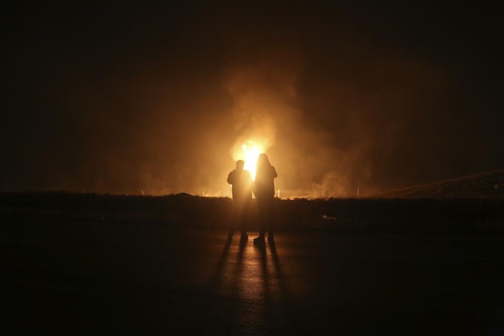 Two men look at flames after a natural gas pipeline explodes outside the city of Boroujen in the western Chaharmahal and Bakhtiari province, Iran, in early Wednesday, Feb. 14, 2024. Explosions struck a natural gas pipeline in Iran early Wednesday, with an official blaming the blasts on a