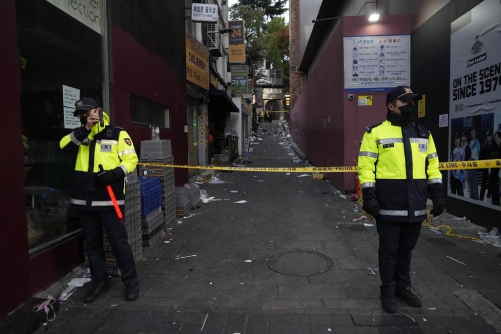 FILE - Police officers stand guard at the scene where people died and were injured in Seoul, South Korea on Oct. 30, 2022, after a mass of mostly young people celebrating Halloween festivities in Seoul became trapped and crushed as the crowd surged into a narrow alley. A South Korean court on Wednesday, Feb. 14m 2024, convicted three former police officers of destroying internal files and other evidence in an attempted cover-up of a Halloween crowd crush that killed nearly 160 people in the capital, Seoul, in 2022. They were the first convictions over the deaths. (AP Photo/Ahn Young-joon, File)