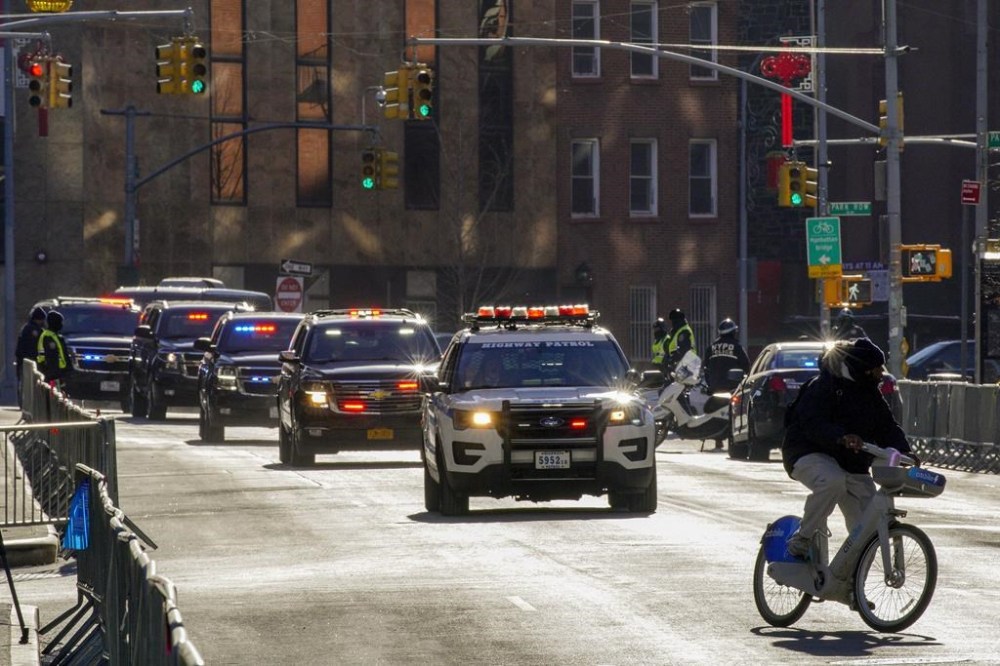 A cyclist crosses in front of Donald Trump's motorcade as it makes its way to Manhattan criminal court, Thursday, Feb. 15, 2024, in New York. Trump is expected to be back in a New York court Thursday for a hearing that could decide whether the former president's first criminal trial begins in just 39 days. (AP Photo/Eduardo Munoz Alvarez)