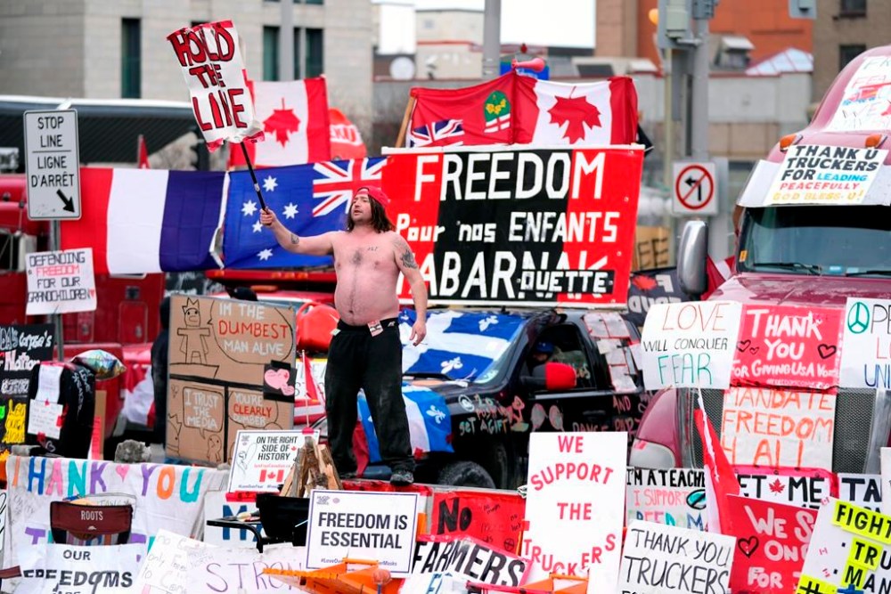 Representatives of the so-called Freedom Convoy are planning to hold a press conference in Ottawa this afternoon, two years after the police action that ended the occupation of downtown Ottawa streets. A protester dances on a concrete jersey barrier in front of vehicles and placards on Rideau Street in Ottawa, on Wednesday, Feb. 16, 2022. THE CANADIAN PRESS/Justin Tang