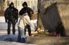 Police officers watch a woman laying flowers to pay tribute to Alexei Navalny at the monument, a large boulder from the Solovetsky islands, where the first camp of the Gulag political prison system was established in St. Petersburg, Russia, Sunday, Feb. 18, 2024. Russians across the vast country streamed to ad-hoc memorials with flowers and candles to pay tribute to Alexei Navalny, the most famous Russian opposition leader and the Kremlin's fiercest critic. Russian officials reported that Navalny, 47, died in prison on Friday. (AP Photo/Dmitri Lovetsky)