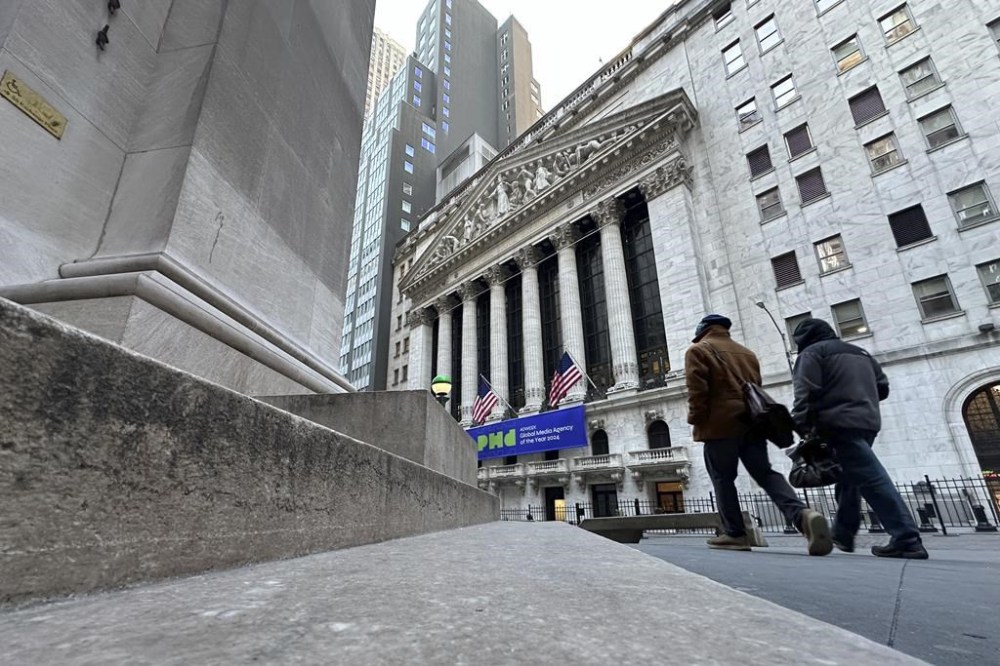 Pedestrians pass the New York Stock Exchange, rear, on Tuesday, Feb. 20, 2024 in New York. (AP Photo/Peter Morgan)