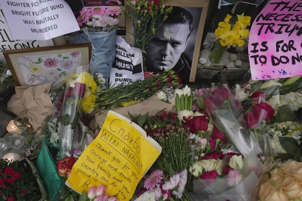 FILE - Flowers and portraits are left opposite the Russian embassy, to commemorate the death of Alexei Navalny in London, Monday, Feb. 19, 2024. European Union countries have approved a new package of sanctions against Russia. The move on Wednesday coincides with the second anniversary of Russia’s full-scale invasion and comes days after the death of Russian opposition leader Alexei Navalny. (AP Photo/Kin Cheung, File)