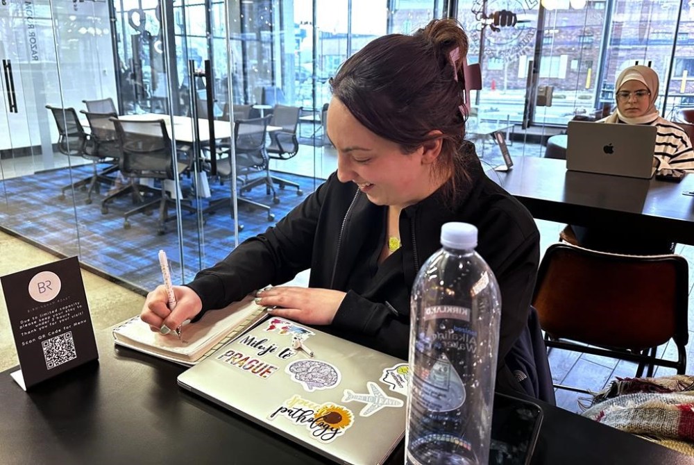 Madeleine Byrnes, a master's degree candidate studying speech pathology at Wayne State University, writes in a notebook in Birmingham, Mich., Feb. 15, 2024. In Michigan, a state that both major parties say they must have to win the White House in 2024, a cloud of apathy has settled over the electorate. Byrnes, a 25-year-old Republican from Oakland County, says she sees signs of slowing in President Joe Biden, but that former President Donald Trump