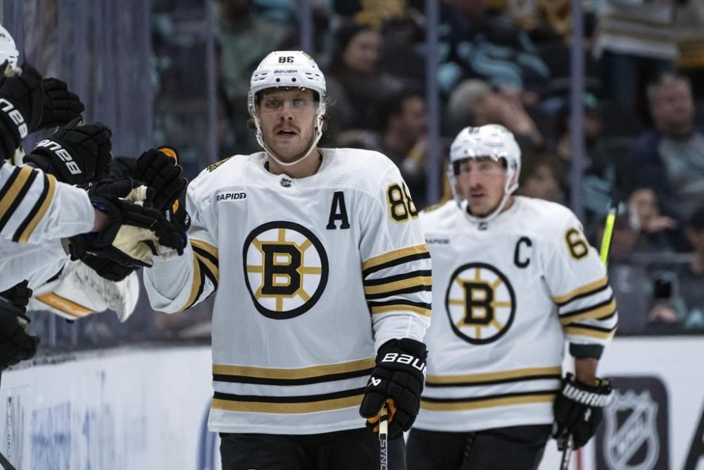 Boston Bruins forward David Pastrnak is congratulated by teammates on the bench after scoring against the Seattle Kraken during the second period of an NHL hockey game, Monday, Feb. 26, 2024, in Seattle. (AP Photo/Stephen Brashear)