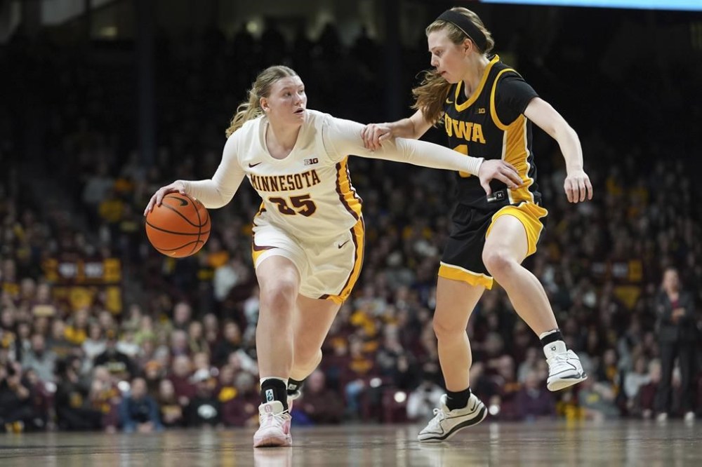 Minnesota guard Grace Grocholski, left, works toward the basket as Iowa guard Molly Davis defends during the first half of an NCAA college basketball game Wednesday, Feb. 28, 2024, in Minneapolis. (AP Photo/Abbie Parr)