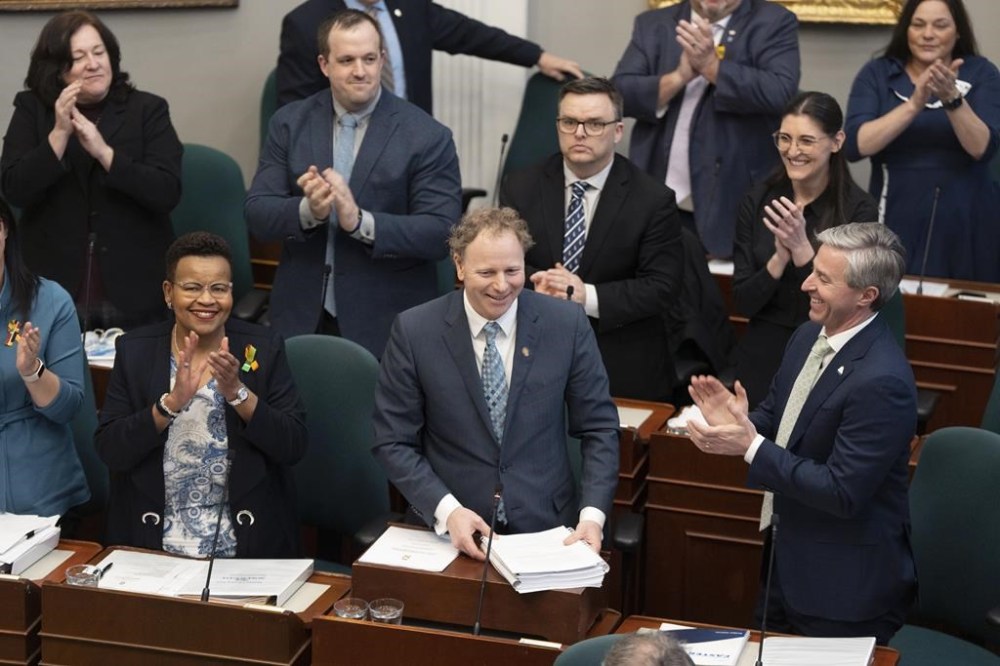 Finance and Treasury Board Minister Allan MacMaster, bottom centre, is applauded by Party members while tabling the provincial budget at the Nova Scotia legislature in Halifax, Thursday, Feb. 29, 2024. THE CANADIAN PRESS/Darren Calabrese