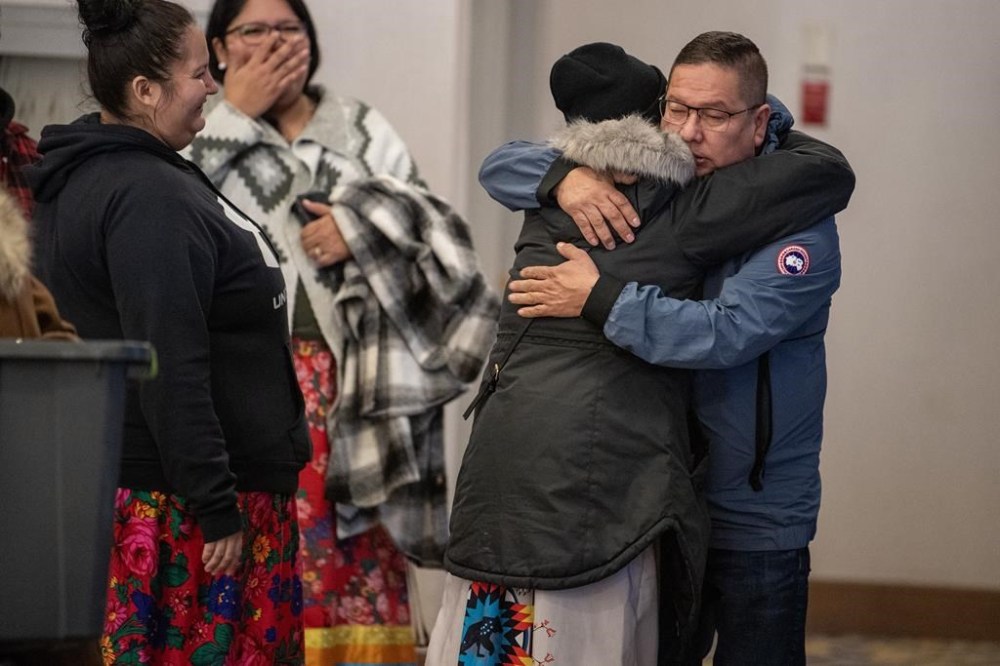 Chief Wally Burns of the James Smith band hugs a community member following the closing of the inquest into the death of Myles Sanderson, who killed 11 people and injured 17 others on James Smith Cree Nation and the nearby community of Weldon in September 2022, held at a hotel conference room in Saskatoon, Thursday, Feb. 29, 2024. THE CANADIAN PRESS/Liam Richards