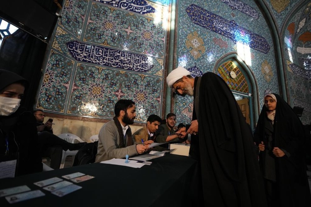 A cleric receives his ballot paper during the parliamentary and Assembly of Experts elections at a polling station in Tehran, Iran, Friday, March 1, 2024. Iran began voting Friday in its first elections since the mass 2022 protests over its mandatory hijab laws after the death of Mahsa Amini, with questions looming over just how many people will turn out for the poll. (AP Photo/Vahid Salemi)