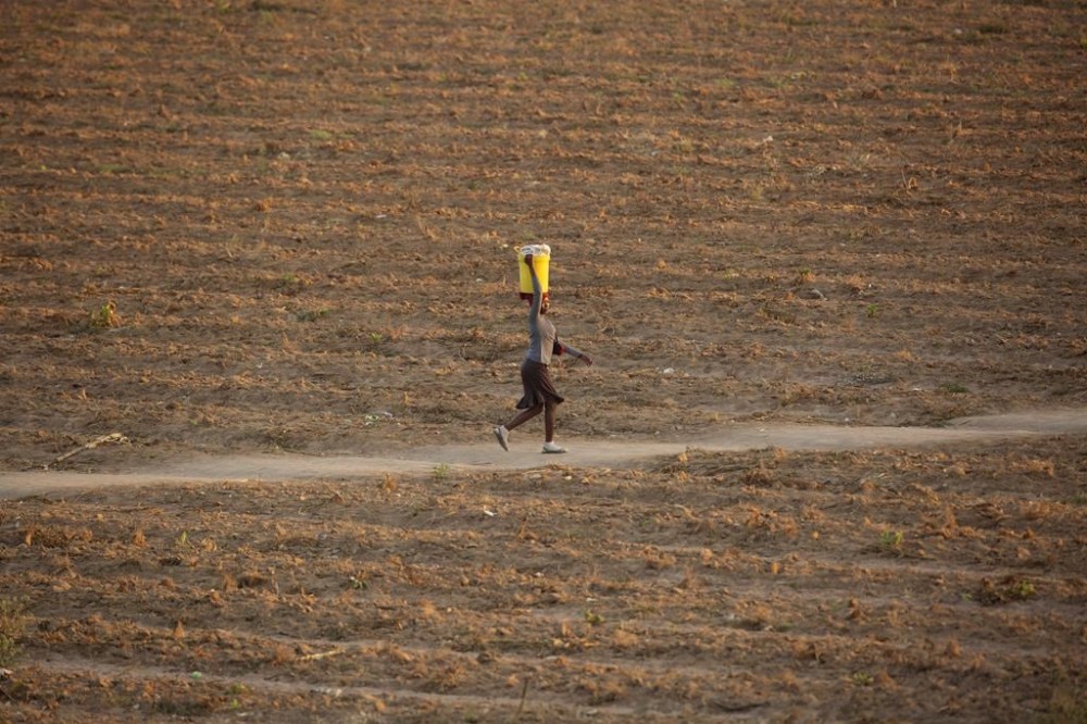 FILE - A woman walks along a path in a deserted field in Zvimba, rural Zimbabwe, on June, 26, 2021. Women who run farms and rural households in poor countries suffer more from climate change and are discriminated against as they try to adapt to other sources of income in times of crises, the United Nations warned Tuesday, March 5, 2024. A new report by the Food and Agriculture Organization, “The Unjust Climate,” found that female-headed rural households lose on average 8% more of their income during heat waves and 3% more during floods, compared to male-headed households. (AP Photo/Tsvangirayi Mukwazhi, File)