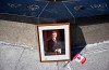 A framed portrait of former prime minister Brian Mulroney leans against the Centennial Flame on Parliament Hill as Canadians mourn his death at the age of 84, in Ottawa, on Friday, March 1, 2024. THE CANADIAN PRESS/Justin Tang