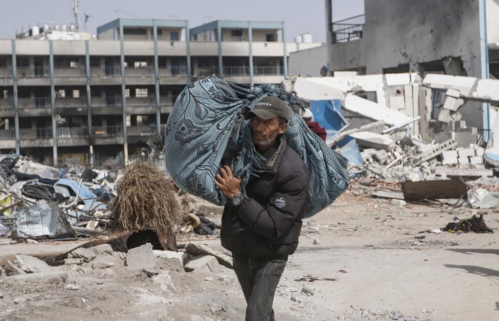 A Palestinian carries his belongings after visiting their houses destroyed in the Israeli offensive on Khan Younis, Gaza Strip, Wednesday, March 6, 2024. (AP Photo/Mohammed Dahman)