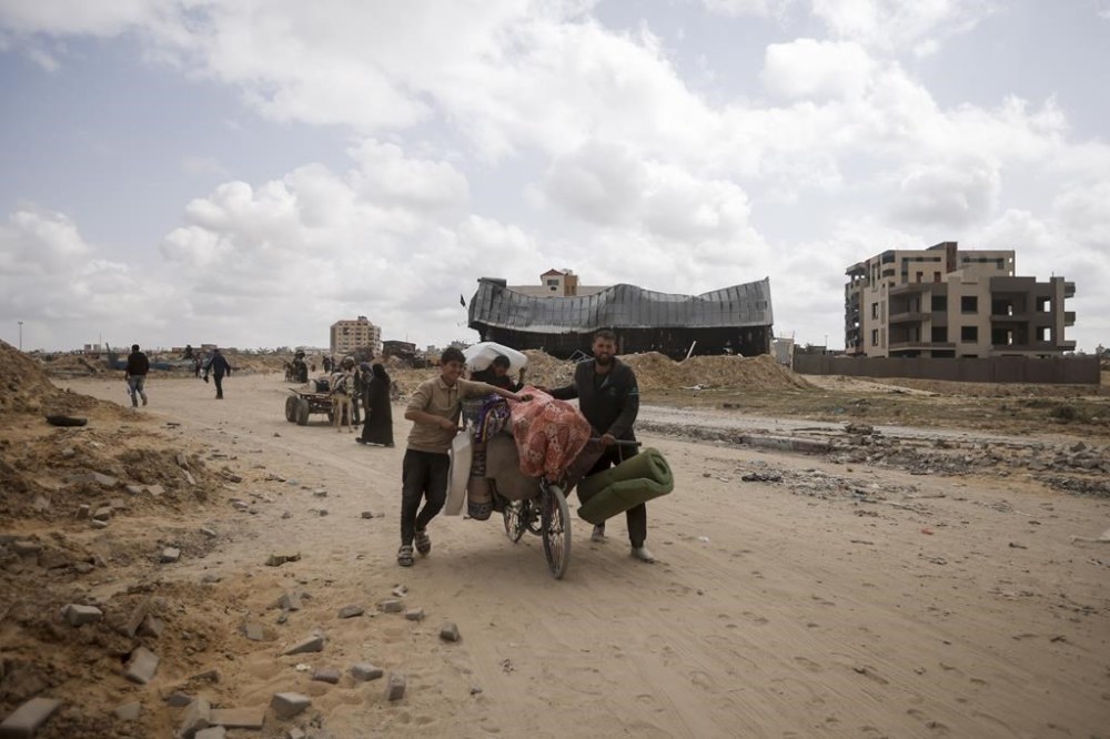Palestinians carry their belonging after visiting their houses destroyed in the Israeli offensive on Khan Younis, Gaza Strip, Wednesday, March 6, 2024. (AP Photo/Mohammed Dahman)