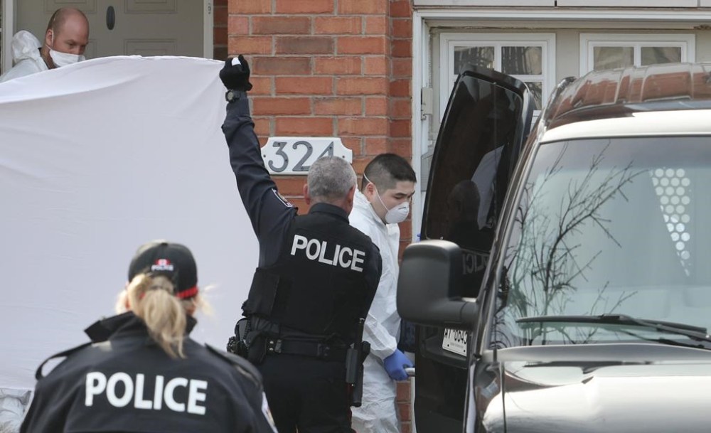 Police officers hold up a sheet as members of the coroner's office remove a body at the scene of a homicide where six people were found dead in the Barrhaven suburb of Ottawa on Thursday, March 7, 2024. THE CANADIAN PRESS/ Patrick Doyle