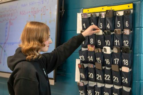 BROOK JONES / WINNIPEG FREE PRESS
                                Grade 12 student Amy Klos puts her cell phone in a cell phone storage pouch fastened to the wall while in her pre-calculus classroom at West Kildonan Collegiate in Winnipeg, Man., Thursday, Feb. 8, 2024. West Kildonan Collegiate is one example among a number of schools across school divisions in Winnipeg that are implementing strict cell phone guidelines for the second semester.