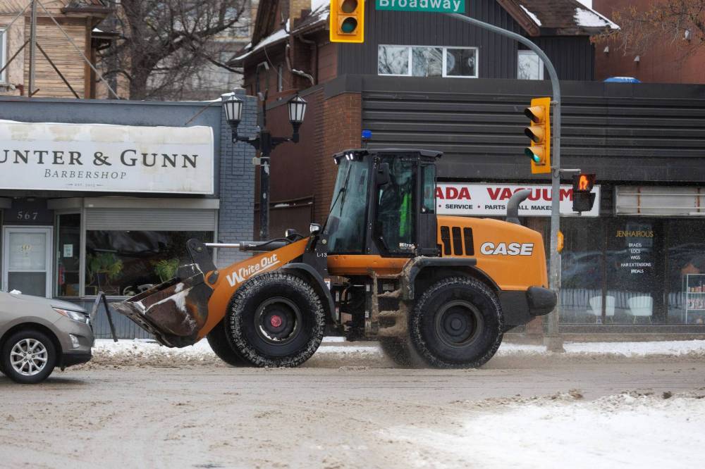 A front-end loader travels down Broadway on Monday. (Mike Deal / Free Press)