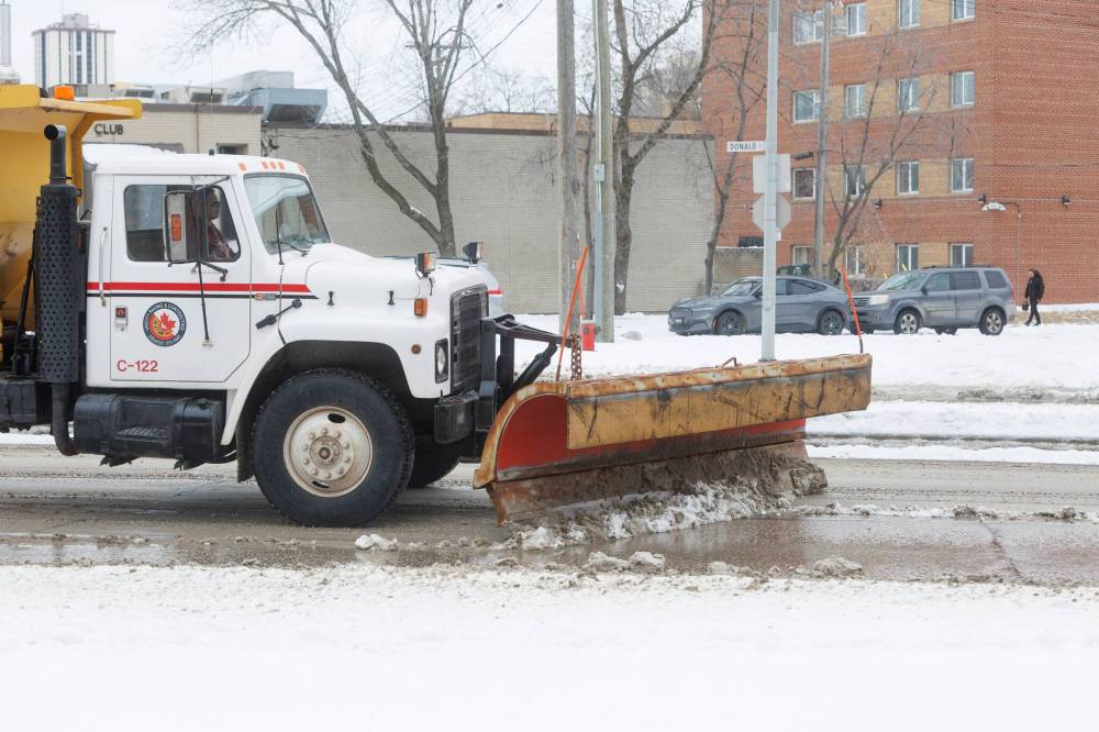 Snow-clearing trucks head north on Donald Street after an overnight storm. (Mike Deal / Free Press)