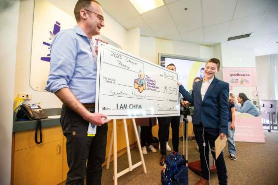 Pacey Wall presents a cheque to Dr. Richard Keijzer, Children’s Hospital pediatric surgery lead, Monday. (Mikaela MacKenzie / Free Press)