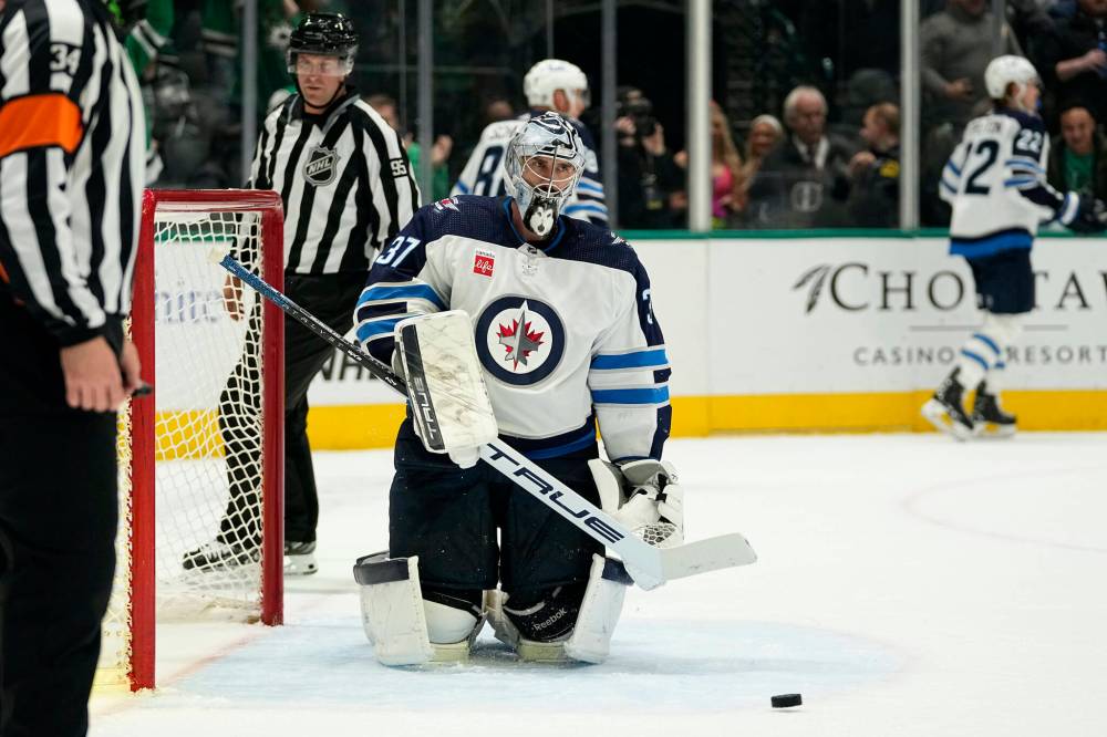 Jets goaltender Connor Hellebuyck fishes the puck out of his net following Logan Stankoven’s first period goal in Dallas, Thursday. (AP Photo/Tony Gutierrez)