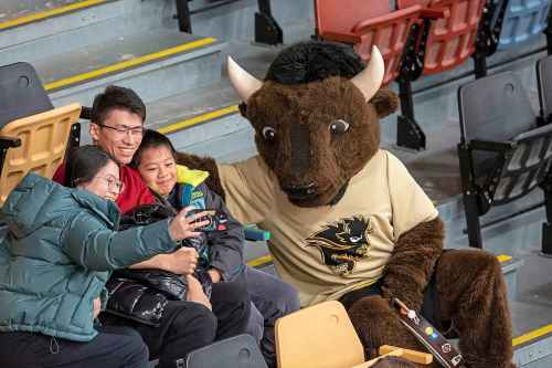 BROOK JONES / WINNIPEG FREE PRESS
The University of Manitoba Bisons host the visiting University of Winnipeg Wesmen in Canada West women's basketball action at the Investors Group Athletic Centre at the University of Manitoba Fort Garry campus in Winnipeg, Man., Saturday, Feb. 3, 2024. Pictured: U of M sports mascot Billy the Bison takes a break from beating the dum to have a selfie taken with basketball fans. Left to Right: Yongxue Lu with her husband Bowen Bu and their nine-year-old son Nemo Bo and Billy the Bison.